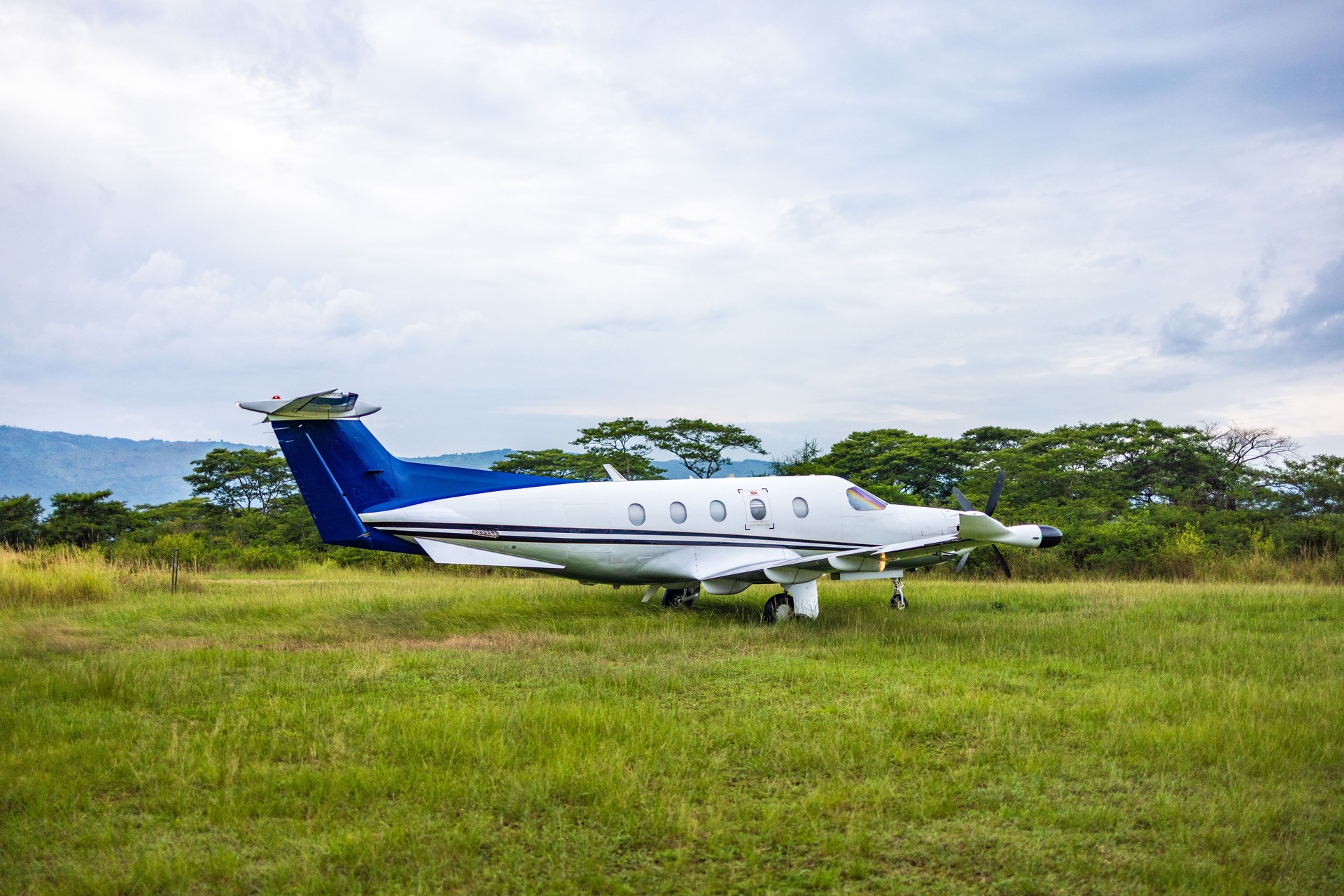 Private Aircraft Stationed on Green Field Under Bright Overcast Sky