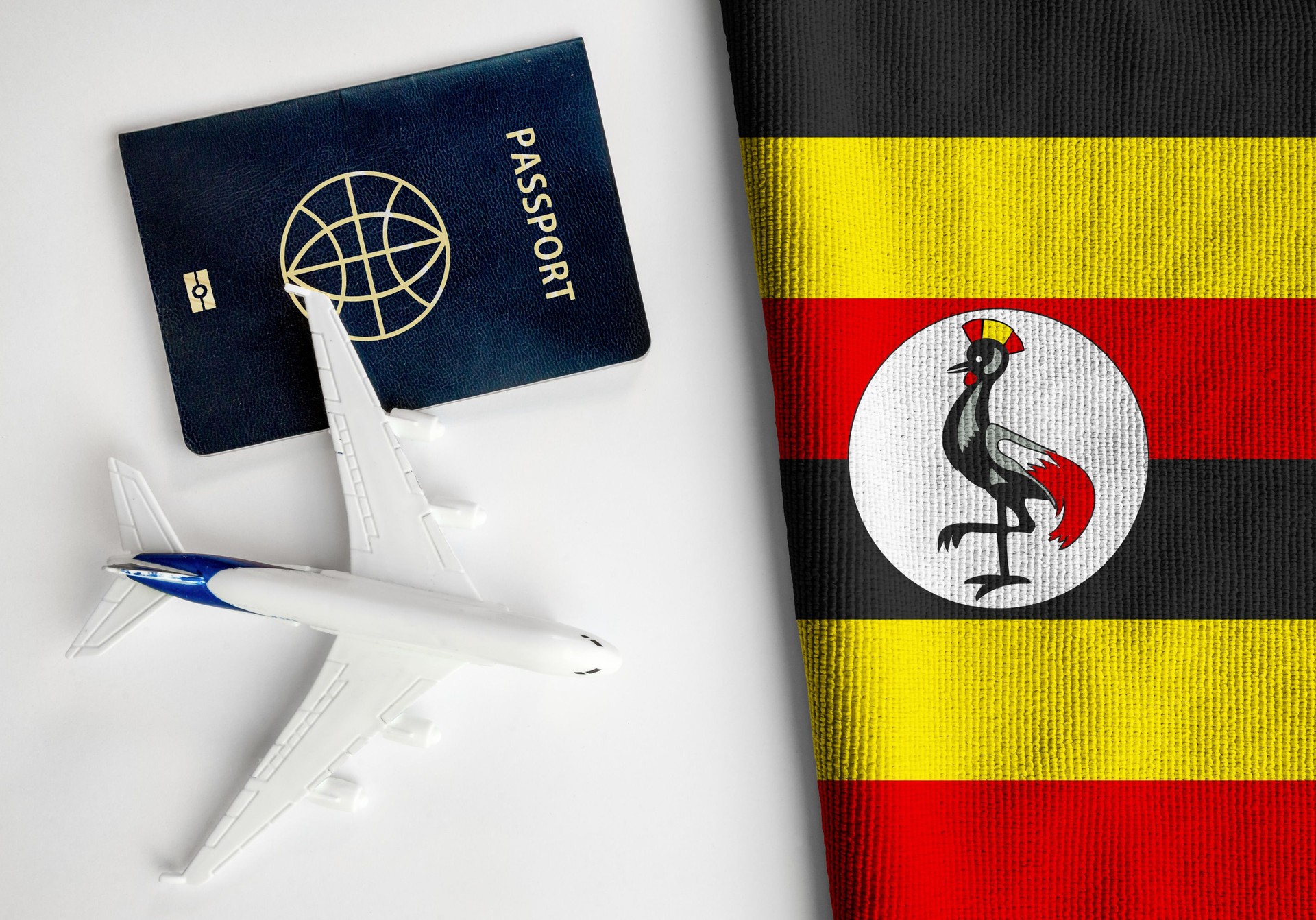 Flag of Uganda with passport and toy airplane.